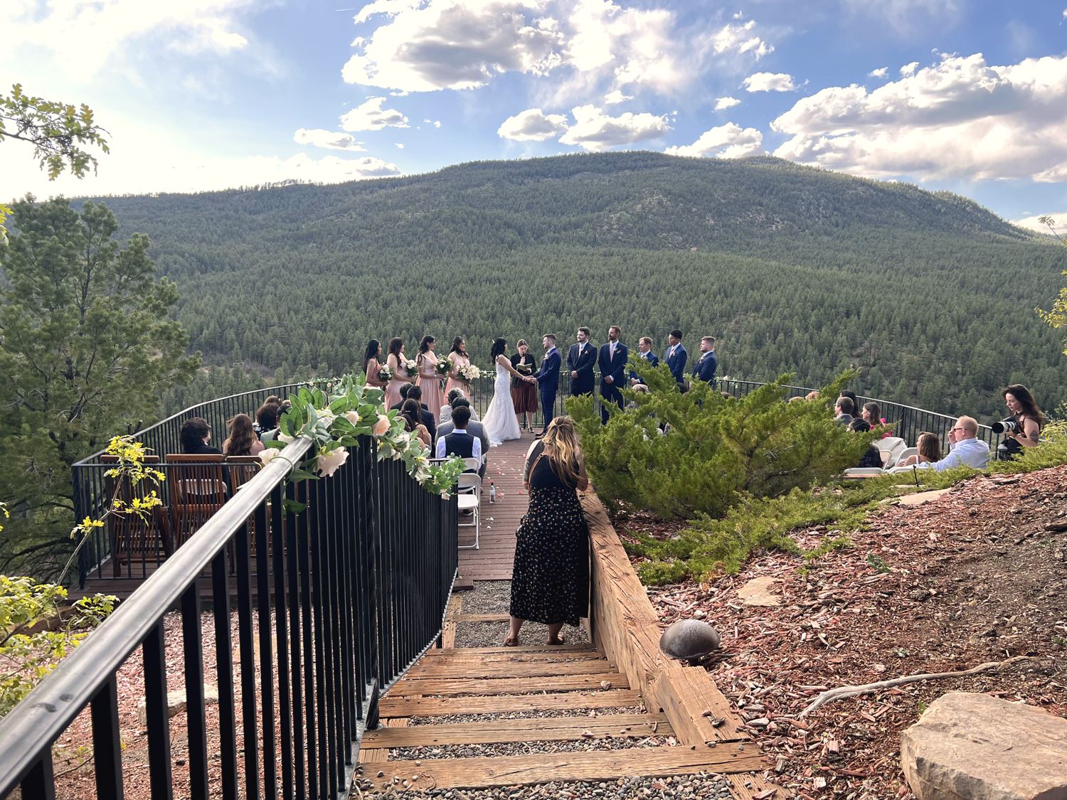 An outdoor cliffside wedding ceremony overlooking a forested valley, with no visible sound equipment