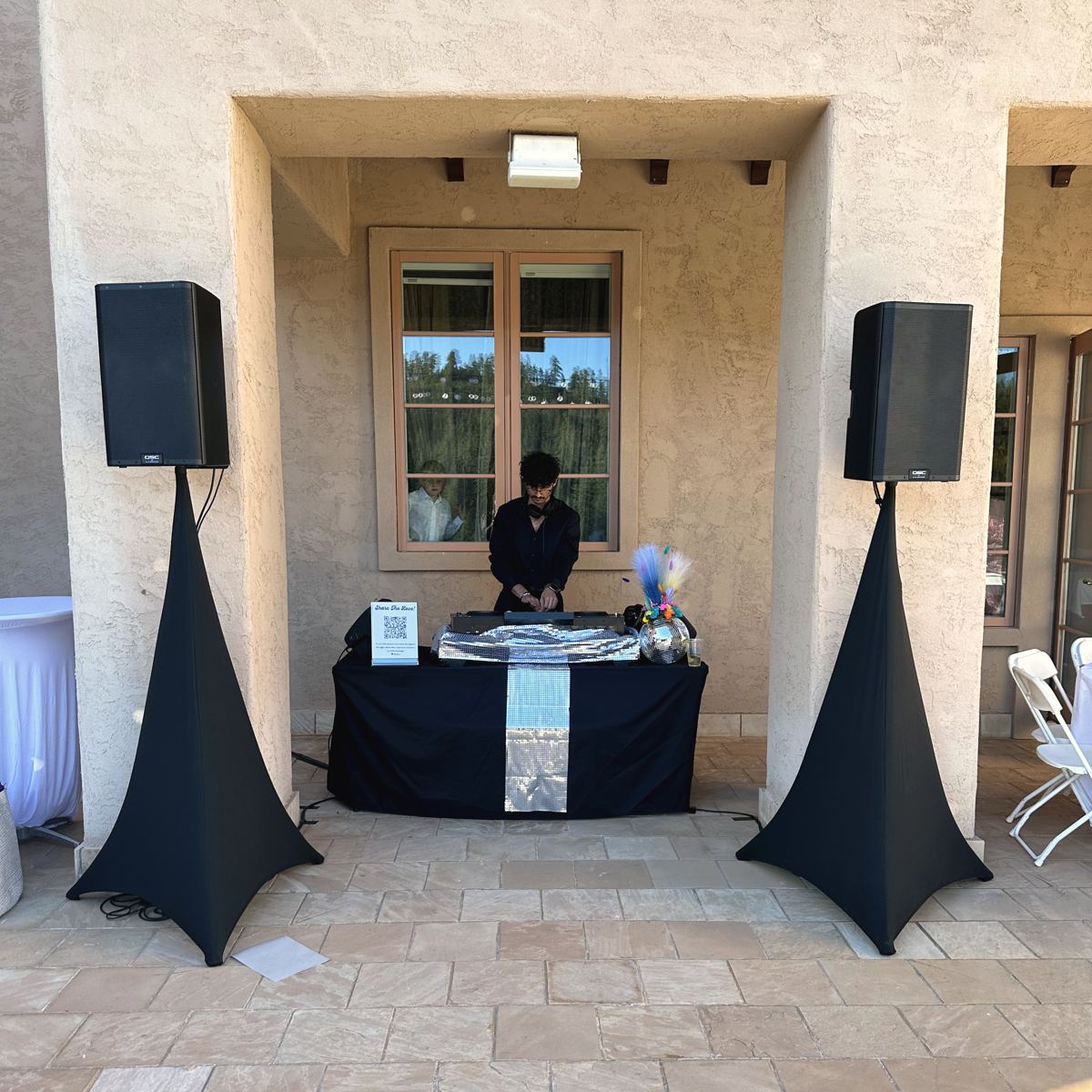 A clean, compact DJ setup with speakers framed in a stone courtyard